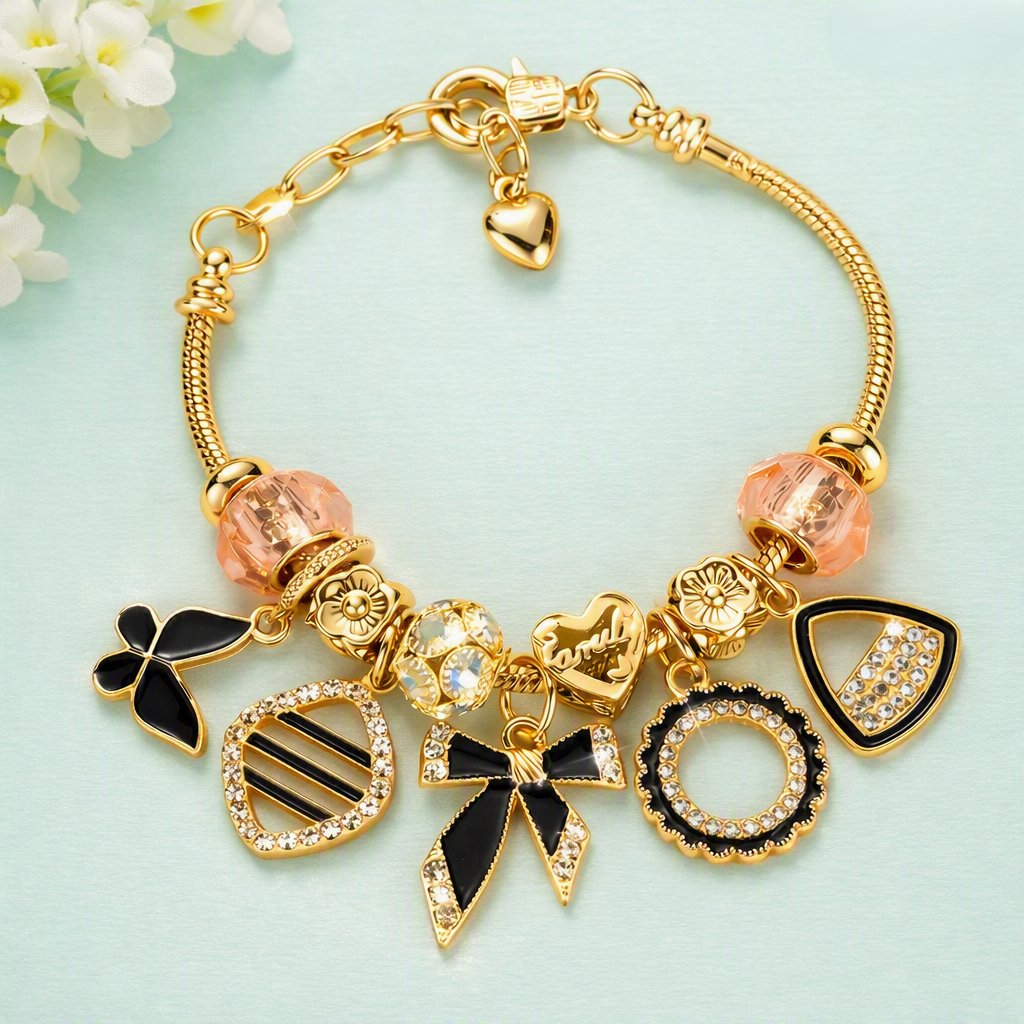 Gold charm bracelet with black enamel and crystal charms on teal background