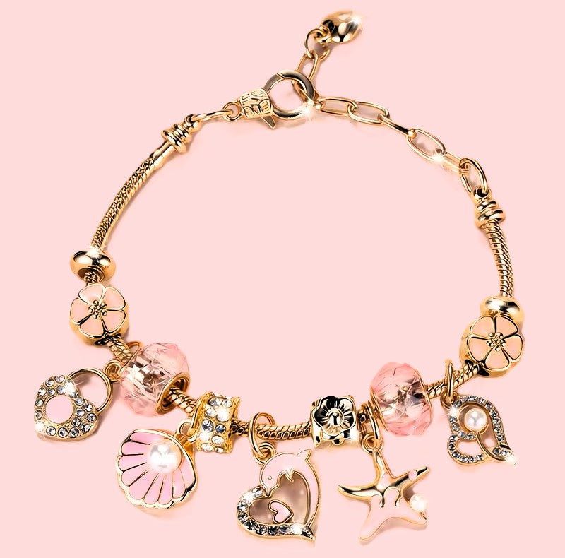 Gold shell and pearl charm bracelet with pink crystal beads on pink background