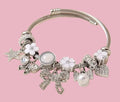 Silver twisted cable bangle bracelet with white enamel and crystal charms on pink background