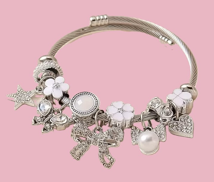 Silver twisted cable bangle bracelet with white enamel and crystal charms on pink background